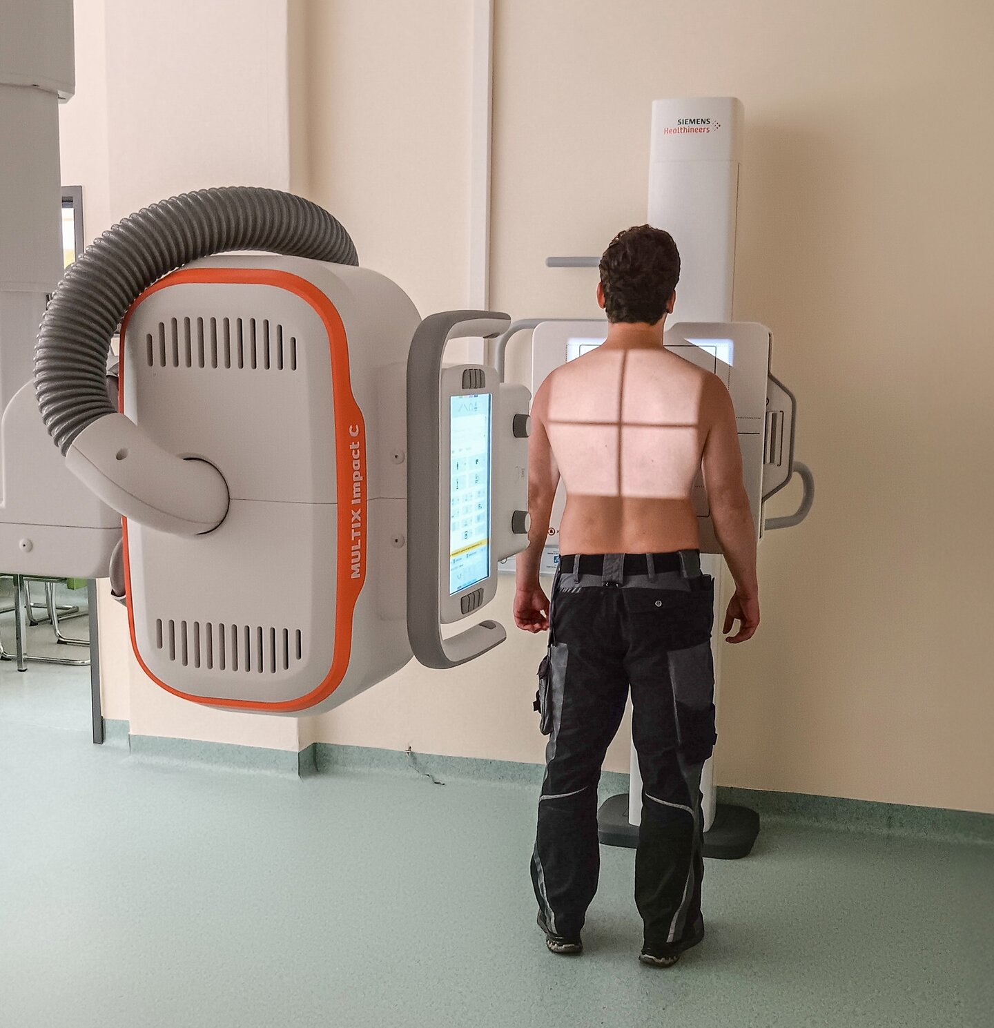 Das Bild zeigt den Rücken eines stehenden Mannes. Auf dem Rücken beleuchtet das neue Röntgengeräte den bildgebenden Bereich.